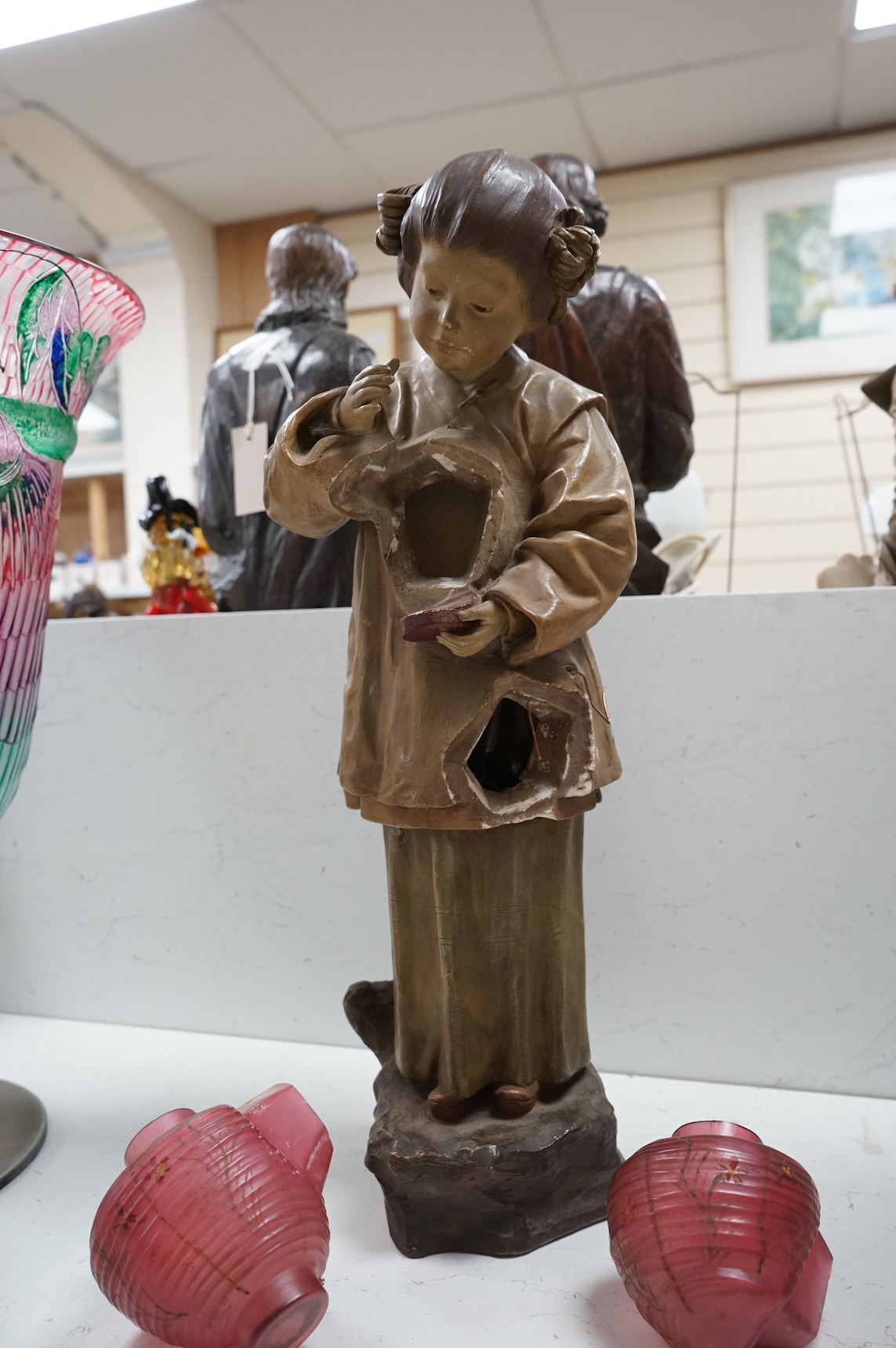 A Goldscheider cold-painted terracotta figural lamp with two cranberry glass shades, 55cm high